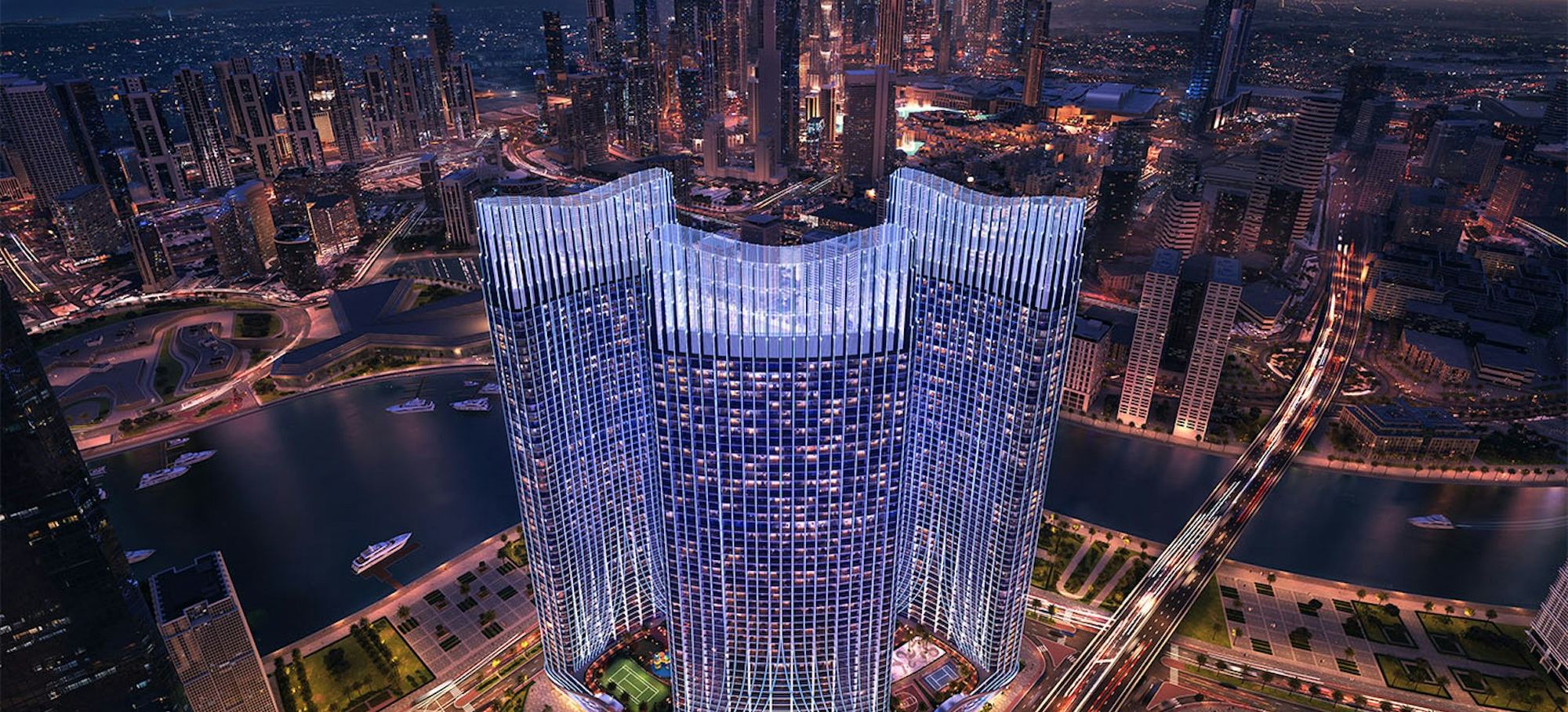 Binghatti Skyrise rising over the Dubai Water Canal in Business Bay at night, with the Downtown skyline behind